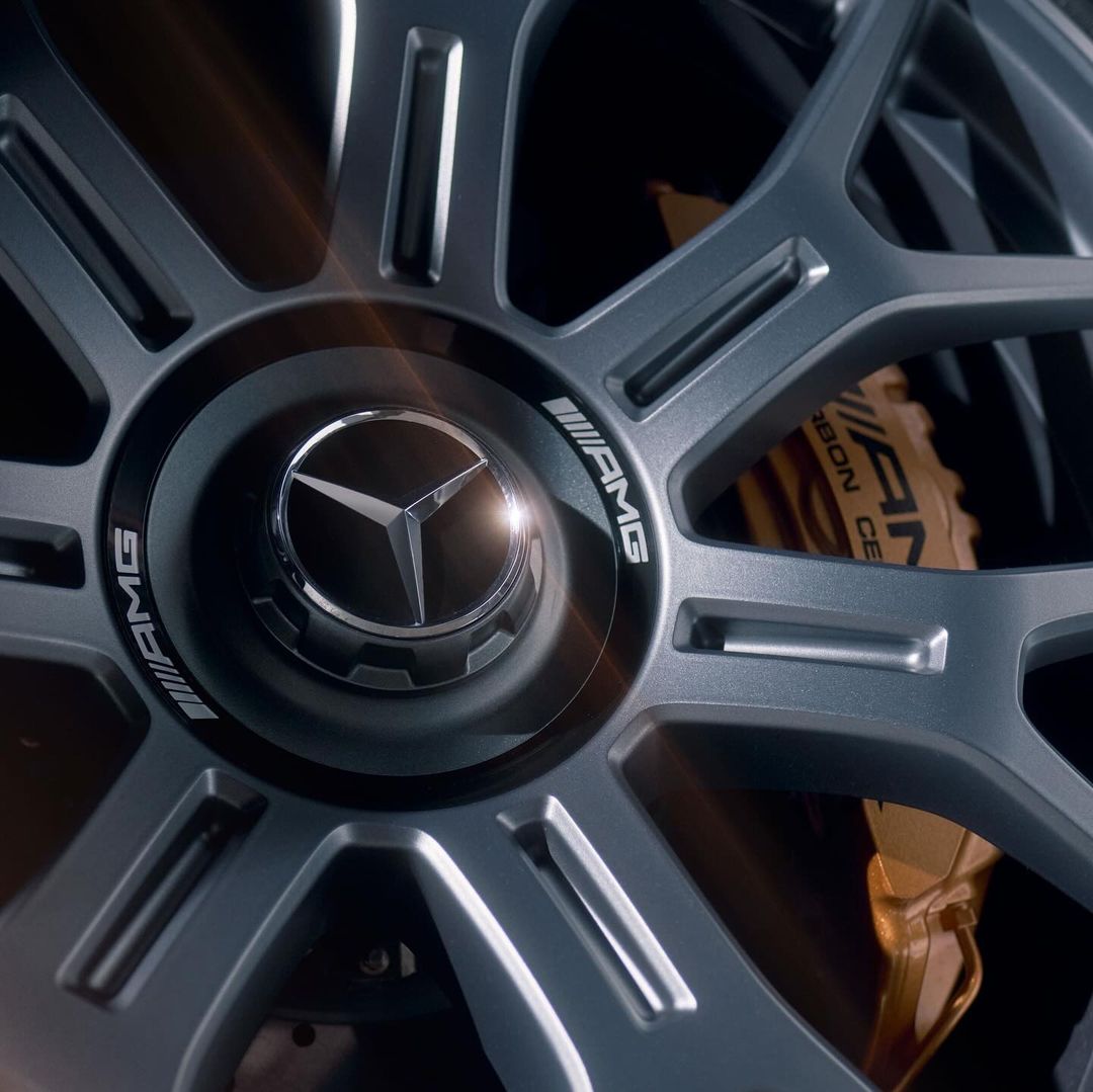 Close-up of a Mercedes-AMG wheel showcasing the intricate design, central logo, brake calliper, and carbon ceramic branding, capturing automotive precision.