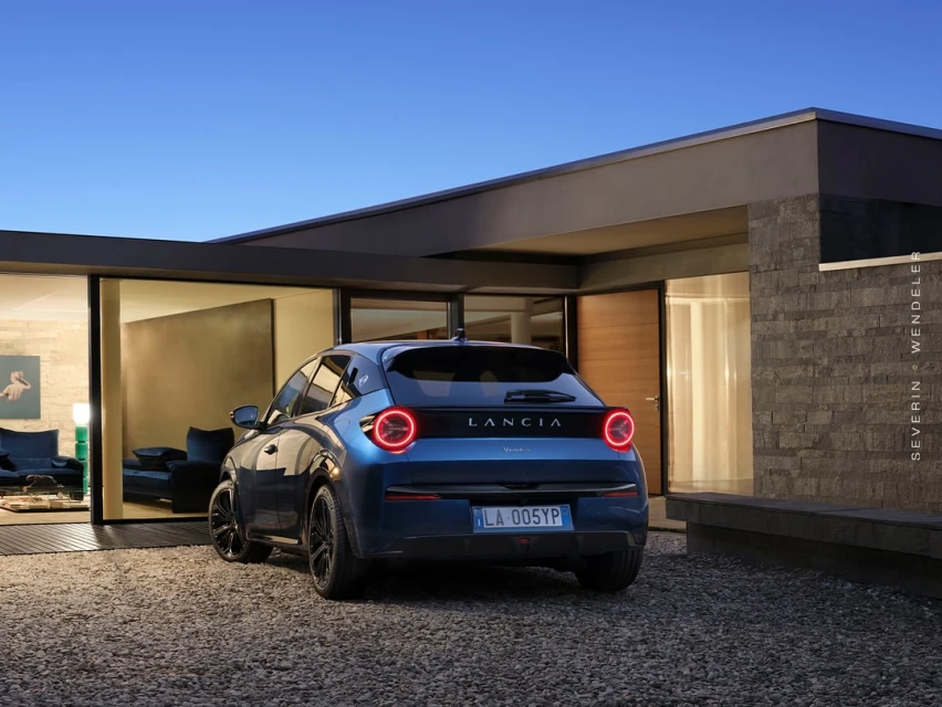 Lancia Gamma parked outside a modern house at dusk, showcasing its elegant design and the surrounding architectural setting.