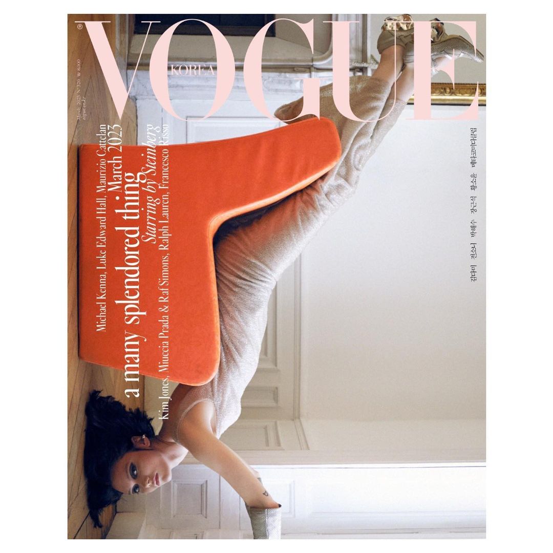 Vogue Korea cover featuring a woman striking a headstand yoga pose in a shimmering dress, positioned beneath an orange T-shaped object.