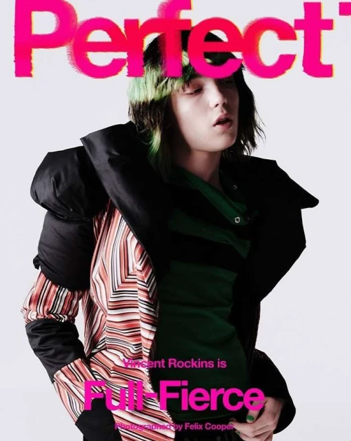 Magazine cover featuring a person with dyed hair, wearing a jacket, and posing in front of a plain white background.