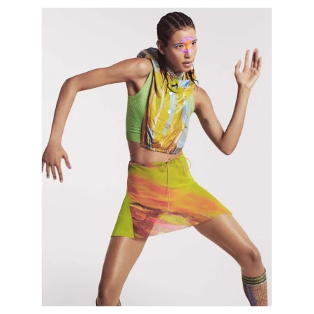 Model in green top and patterned skirt posing dynamically against a white background by Felix Cooper