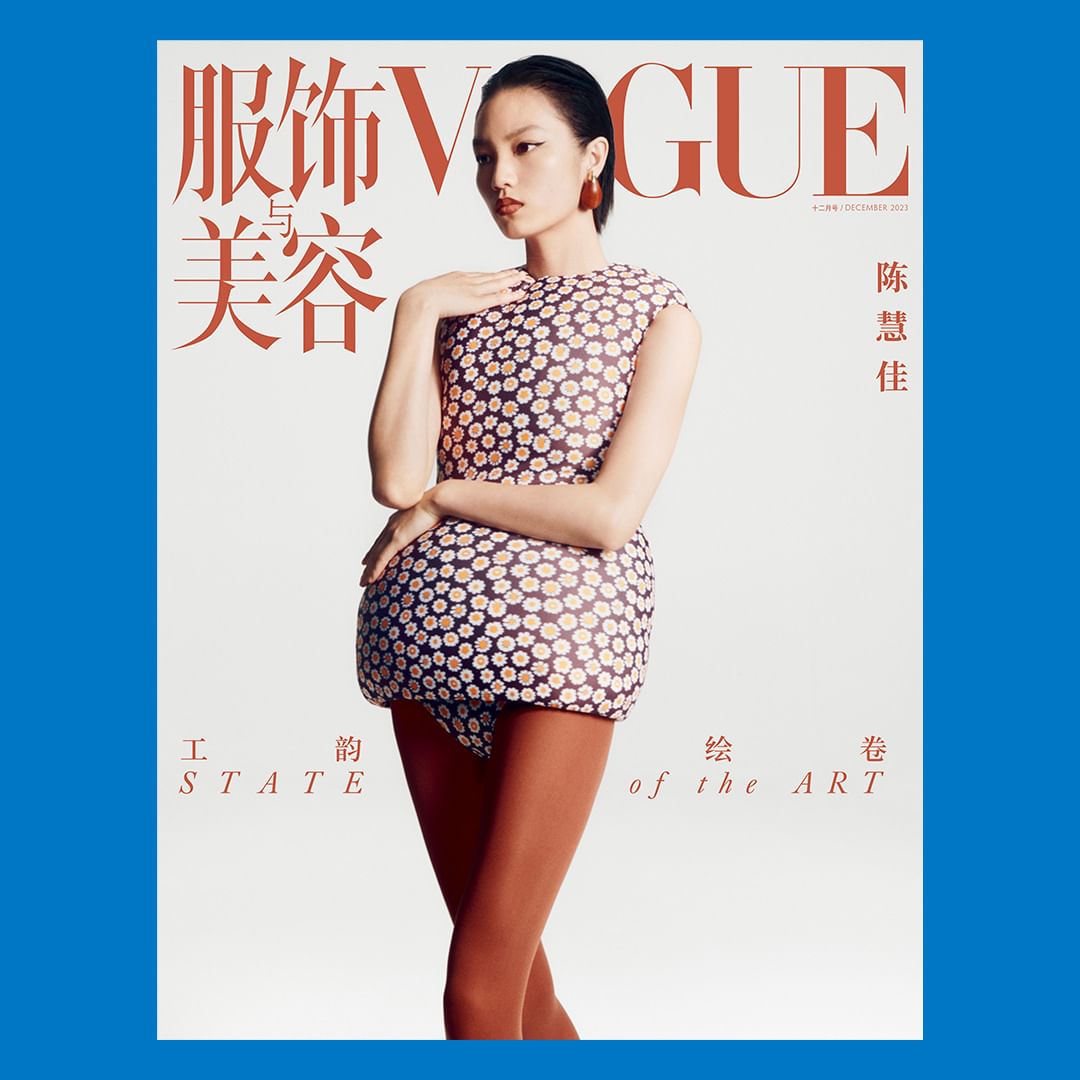Model wearing a structured daisy pattern mini dress and orange tights against a white seamless background