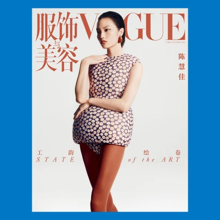 Model wearing a structured daisy pattern mini dress and orange tights against a white seamless background