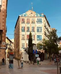 Painted building facade with trompe l oeil architectural details in a city square with pedestrians.