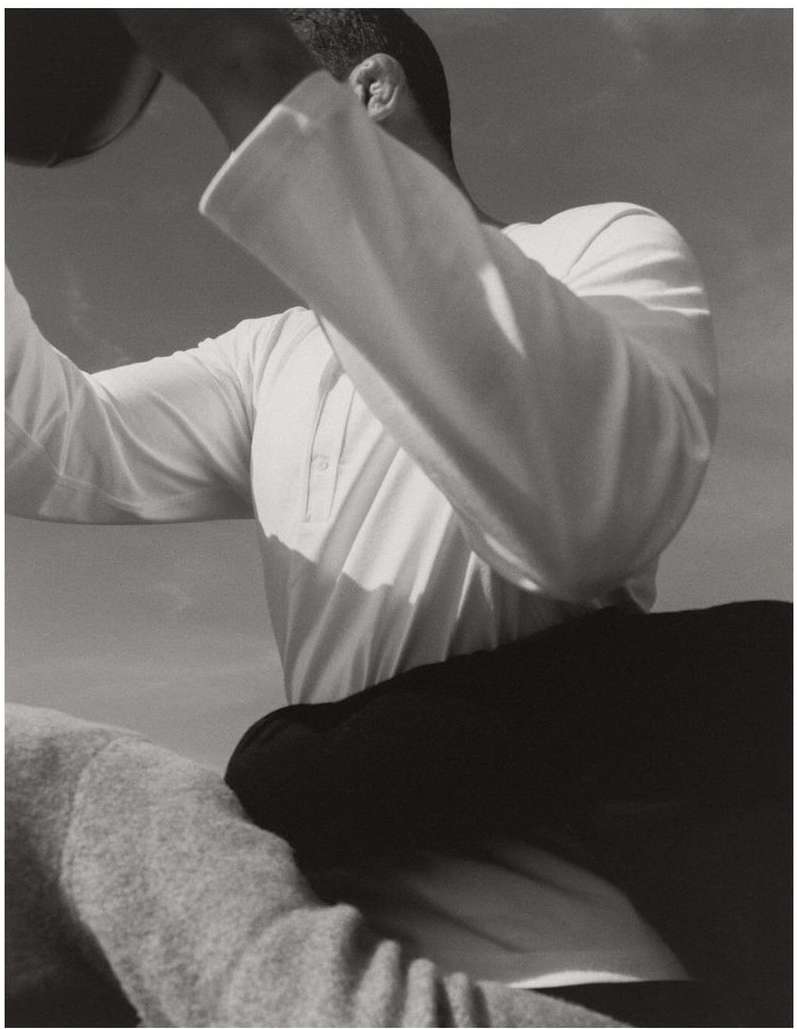 Monochrome image of an adult holding a ball outdoors, showcasing a clear sky and a minimal aesthetic with focus on form and texture.