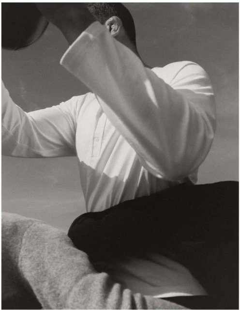 Monochrome image of an adult holding a ball outdoors, showcasing a clear sky and a minimal aesthetic with focus on form and texture.
