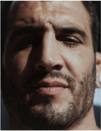 Close-up portrait of a man with short dark hair and facial stubble under directional lighting by Felix Dol Maillot in Paris.