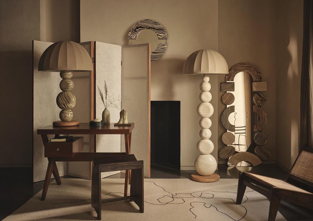 Living room interior featuring modern furniture: table, floor lamp, chair, folding screen, and mirror, with neutral color palette.