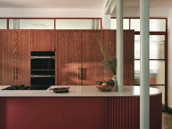 Modern kitchen interior with wood cabinets, a center island, and minimalist decor, showcasing a blend of contemporary design and warm textures.