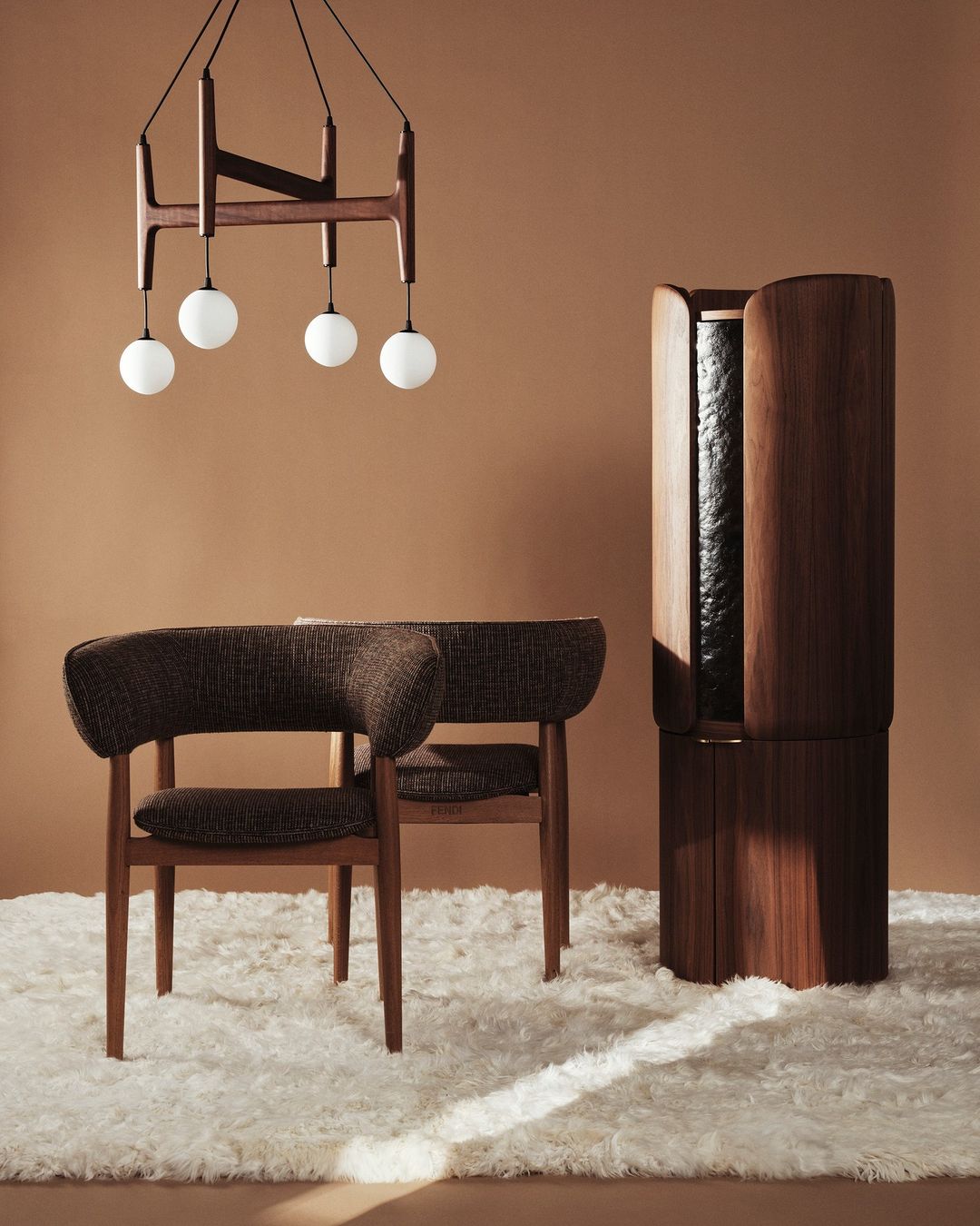 Interior shot of a brown armchair and wooden cabinet on a white rug with a unique chandelier against a brown wall in a well-lit room.
