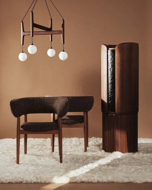 Interior shot of a brown armchair and wooden cabinet on a white rug with a unique chandelier against a brown wall in a well-lit room.