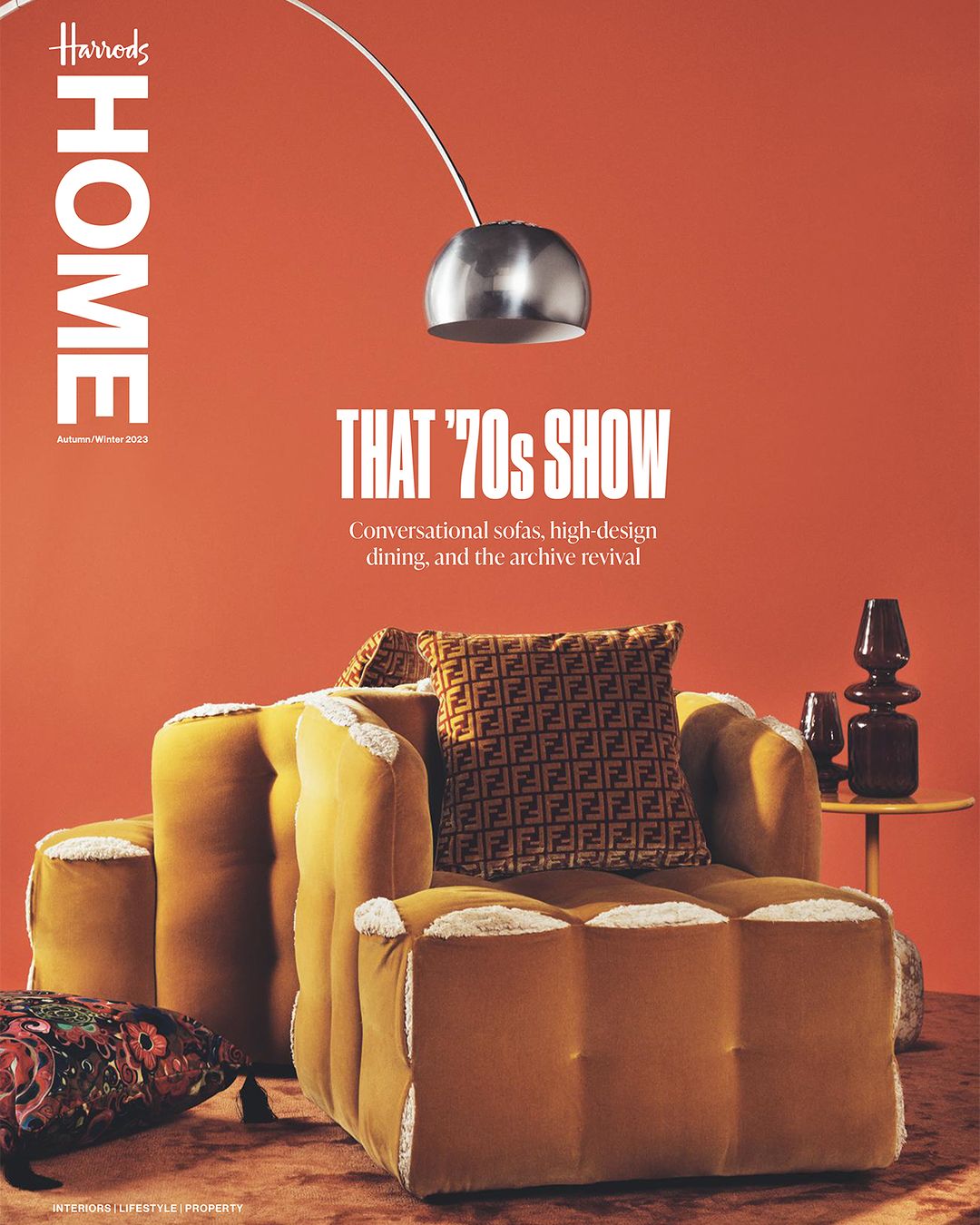 Harrods Home magazine cover featuring an orange backdrop, a lamp, a vase and a brown and yellow sofa with Fendi cushion.