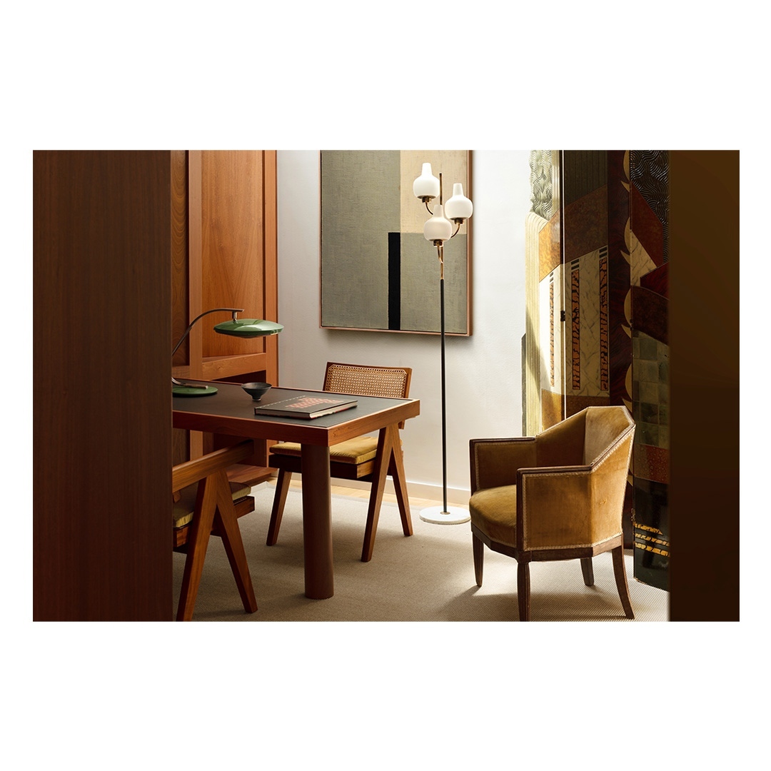 Interior view showcases a desk with a lamp, chair, floor lamp, painting, and wood paneling, creating a stylish and comfortable living space.