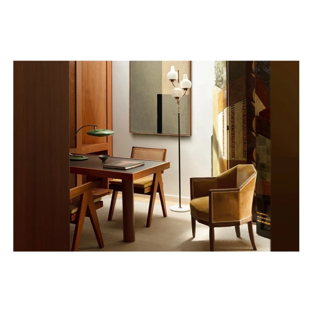 Interior view showcases a desk with a lamp, chair, floor lamp, painting, and wood paneling, creating a stylish and comfortable living space.