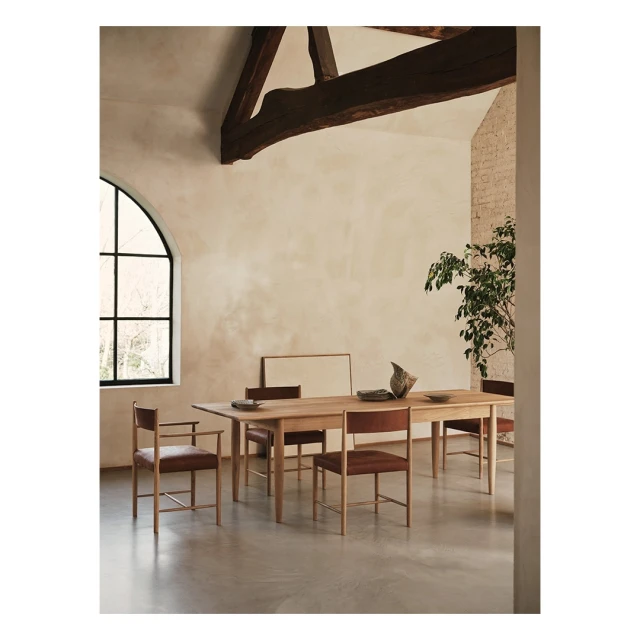 Interior photography of a dining room with a wooden table and chairs, minimalist decor, and natural light from an arched window.