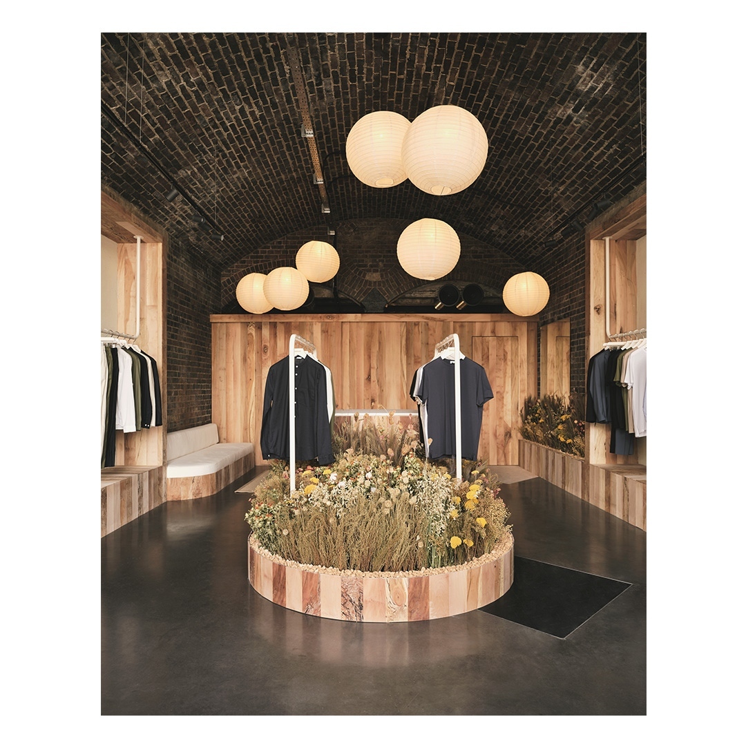 Clothing boutique interior with floral display and hanging garments, illuminated by spherical pendant lights, creating a warm ambiance.
