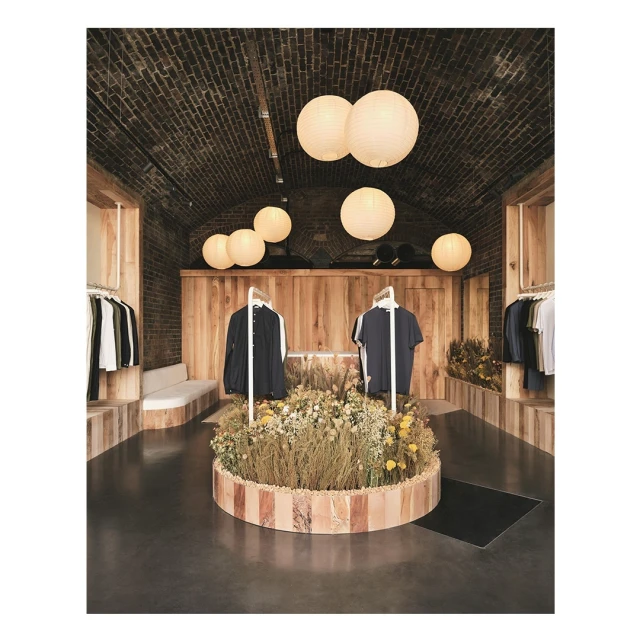 Clothing boutique interior with floral display and hanging garments, illuminated by spherical pendant lights, creating a warm ambiance.