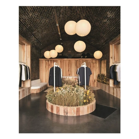 Clothing boutique interior with floral display and hanging garments, illuminated by spherical pendant lights, creating a warm ambiance.