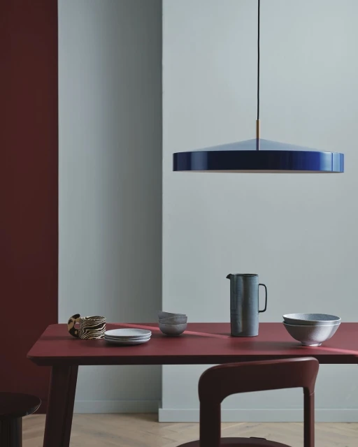Interior design featuring a modern dining room setting with a pendant light, table, chair, and tableware in a minimalist aesthetic.