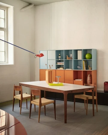 Photo of dining area featuring a wooden table, chairs, and shelving unit in a room with natural light, showcasing interior design elements.
