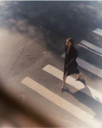 High-angle view of a woman walking across a pedestrian crosswalk in a dark coat and heeled shoes by photographer Felix Wong
