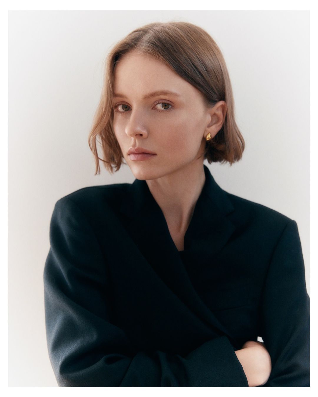 Portrait of a woman with short brown hair wearing a dark blazer against a plain neutral background.