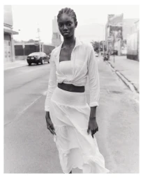 Black and white street portrait of a woman wearing a white buttoned shirt and tiered skirt by photographer Felix Wong