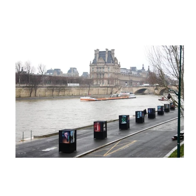 Seine river embankment in Paris with art installations. Buildings and river transport are visible in the background on an overcast day.