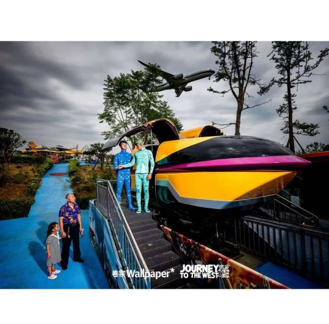 People posing near a futuristic train with plane overhead at an amusement park. Family scene with girl, man, and men in costumes.