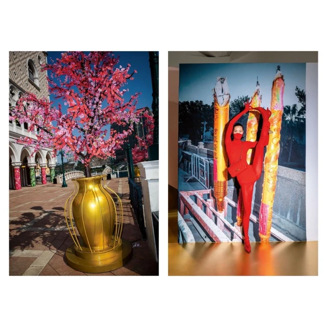 Outdoor display with pink blossom tree in gold vase near building. Woman in red jumpsuit strikes a pose in front of cityscape photo.