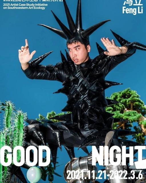 Person in avant-garde spiky black outfit with cactus, sculpture and balloon against blue sky. Text overlays the image, outdoor shot.