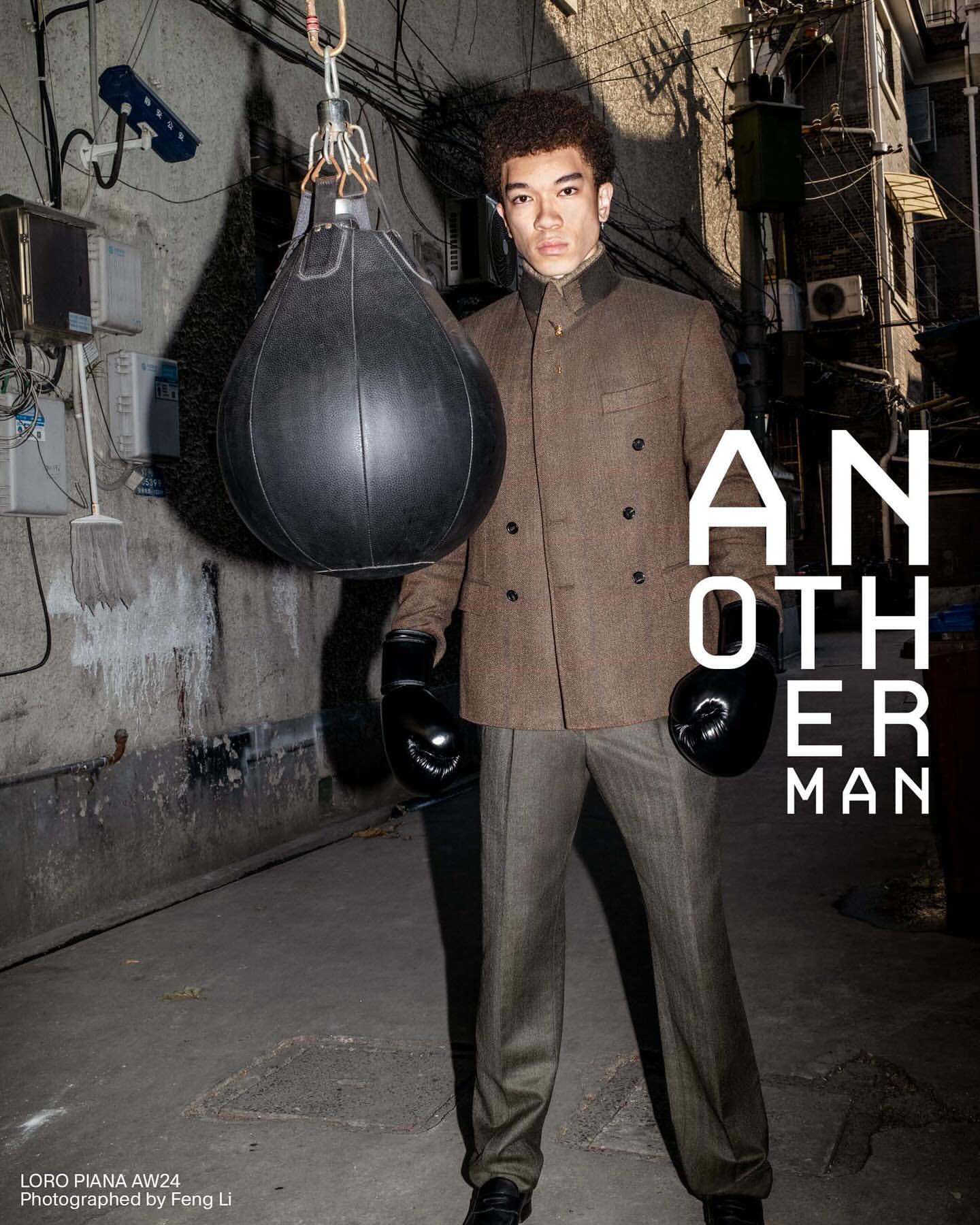 A man wearing boxing gloves and a suit stands in front of a punching bag in an alleyway with exposed pipes and magazine text overlay.