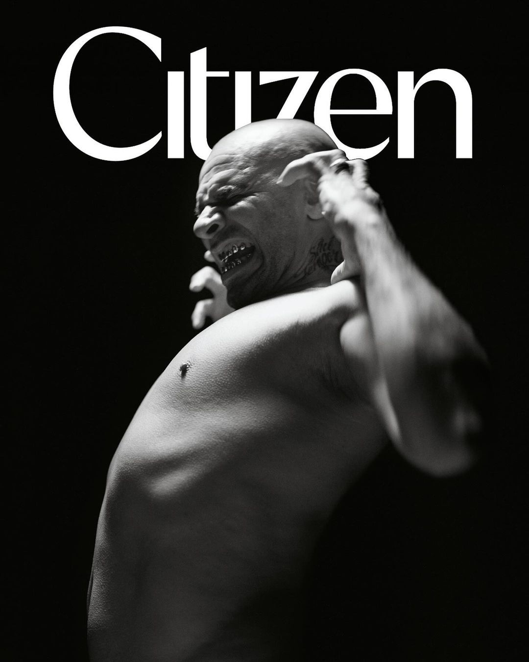A dramatic black and white portrait of a bald man with gold teeth, straining against a black background with the word 'Citizen' above him.