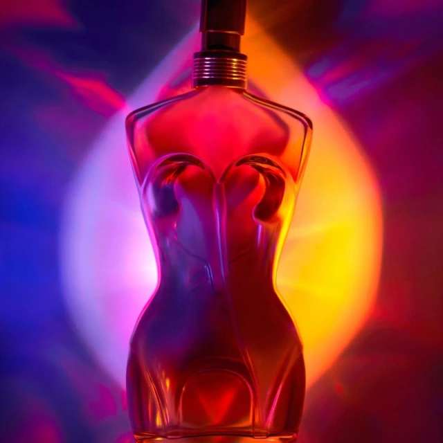 Perfume bottle with a woman's body shape against a colorful background with red, yellow, and blue light, emphasizing the bottle's design.