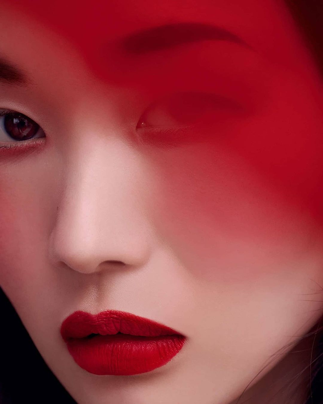 Close-up portrait of a woman with red lips and a red filter covering part of her face, beauty concept with fashion and makeup.