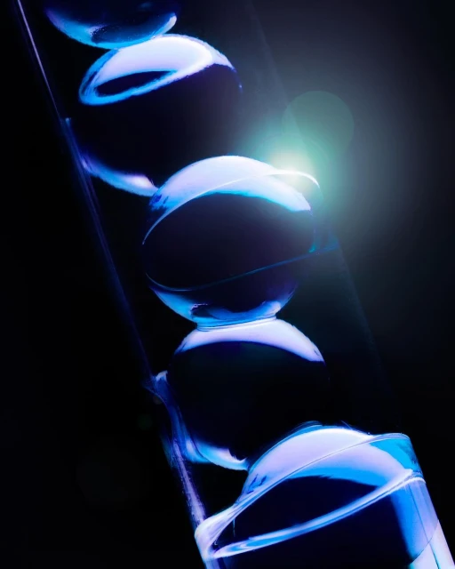 Abstract macro shot of illuminated transparent spheres stacked in a clear tube, creating a mesmerizing visual effect against a dark background.