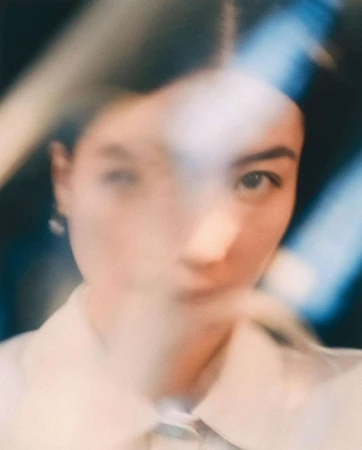 Close-up portrait of a woman viewed through a blurred glass or translucent obstruction by photographer Ferry Mohr.