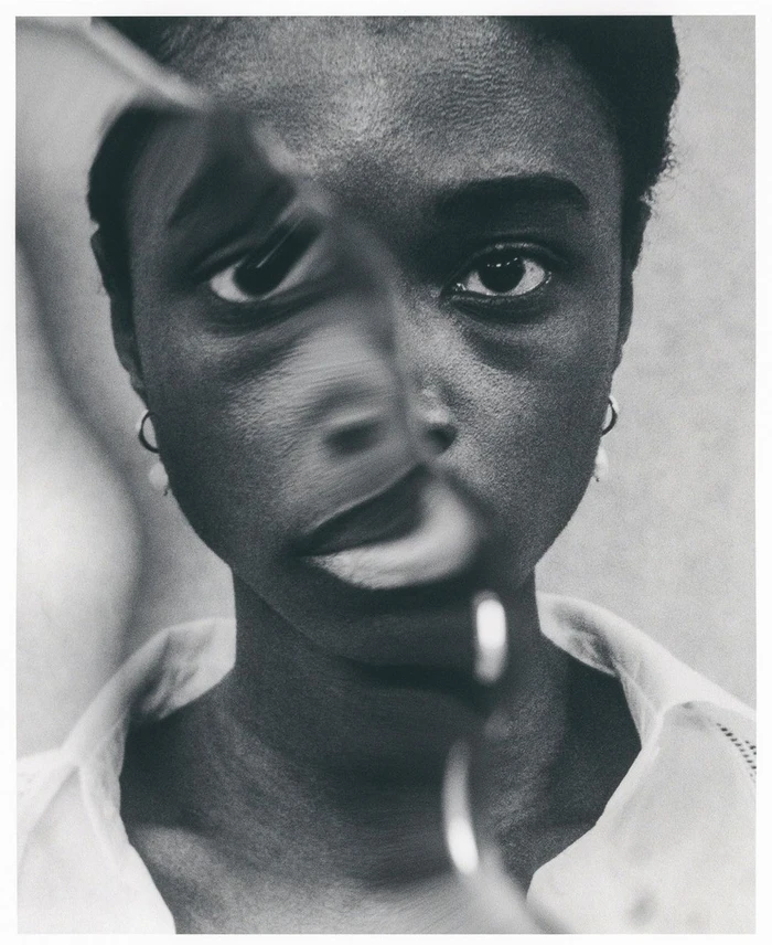 Black-and-white portrait of a woman with a mirrored reflection distorting her facial features, wearing a light-coloured collared shirt