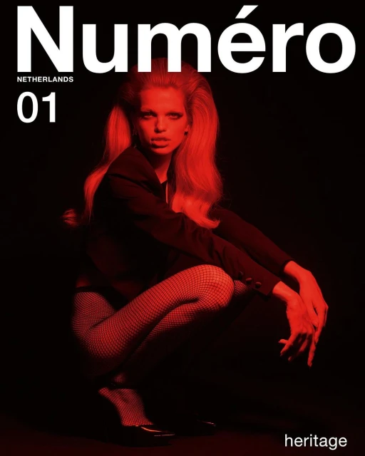 Magazine cover featuring a woman in a crouched position wearing fishnet stockings, a dark jacket, and red lighting on a dark background.