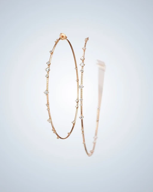 Elegant hoop earrings in rose gold tone, adorned with clear gemstones, are showcased against a soft gradient background.