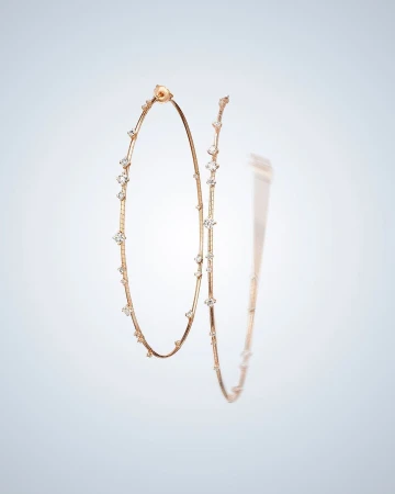 Elegant hoop earrings in rose gold tone, adorned with clear gemstones, are showcased against a soft gradient background.