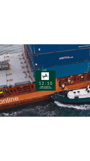 Aerial view of a cargo ship being assisted by a tugboat in the sea, carrying stacked containers on its deck.  Shipping industry.