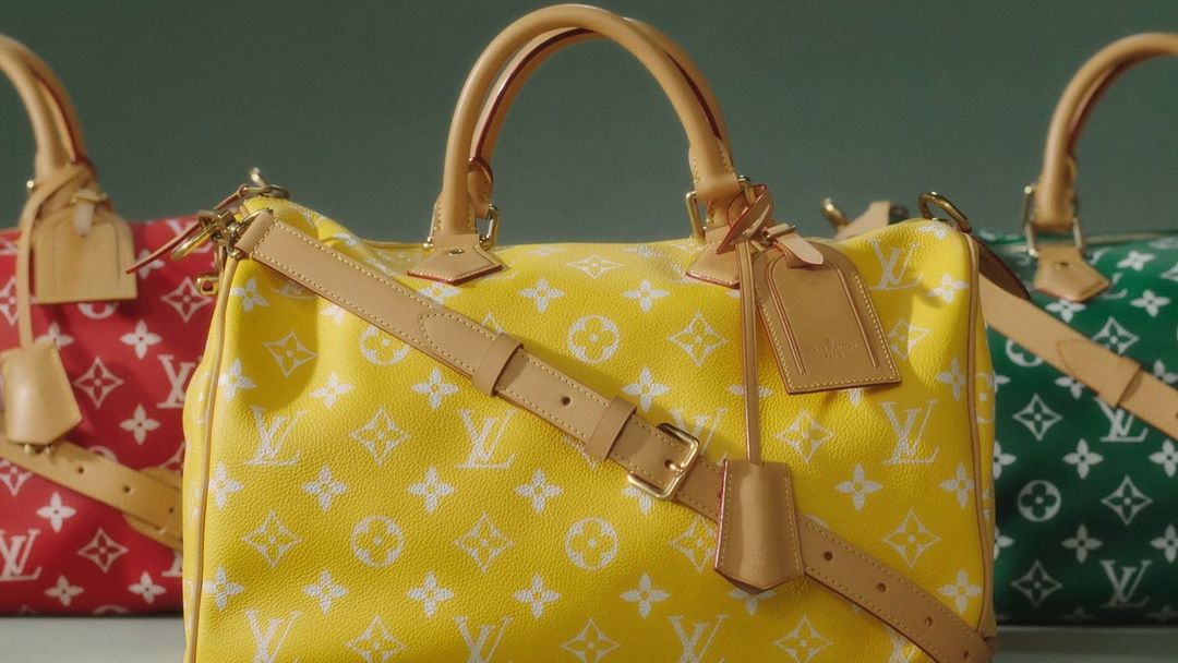 Three colorful Louis Vuitton Speedy bags in red, yellow, and green, arranged in a row. Each bag has a white monogram pattern.