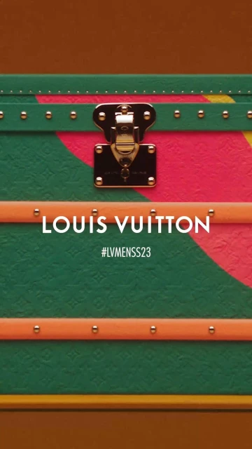 Detailed shot of a Louis Vuitton trunk with a unique orange, green, and pink painted design and gold hardware details.