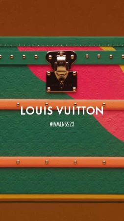 Detailed shot of a Louis Vuitton trunk with a unique orange, green, and pink painted design and gold hardware details.