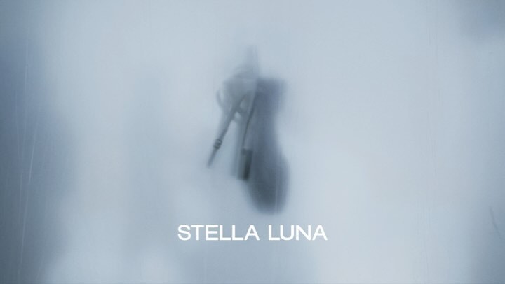 A blurry image of a high heel shoe with a light blue background, overlaid with the text 'STELLA LUNA', creating a soft, dreamy feel.