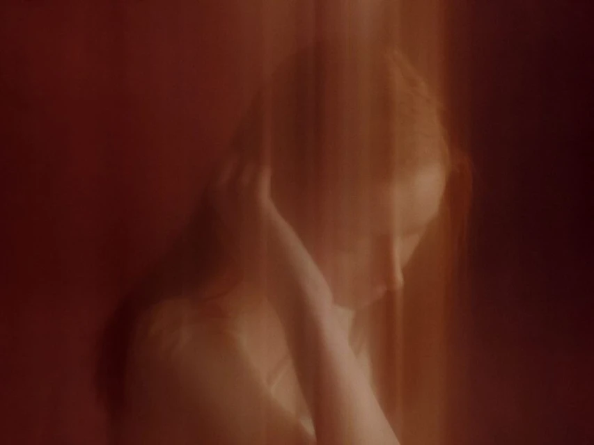 Portrait of an adult female with long red hair, posing indoors with dramatic lighting and blurred motion, in a beauty or fashion context.