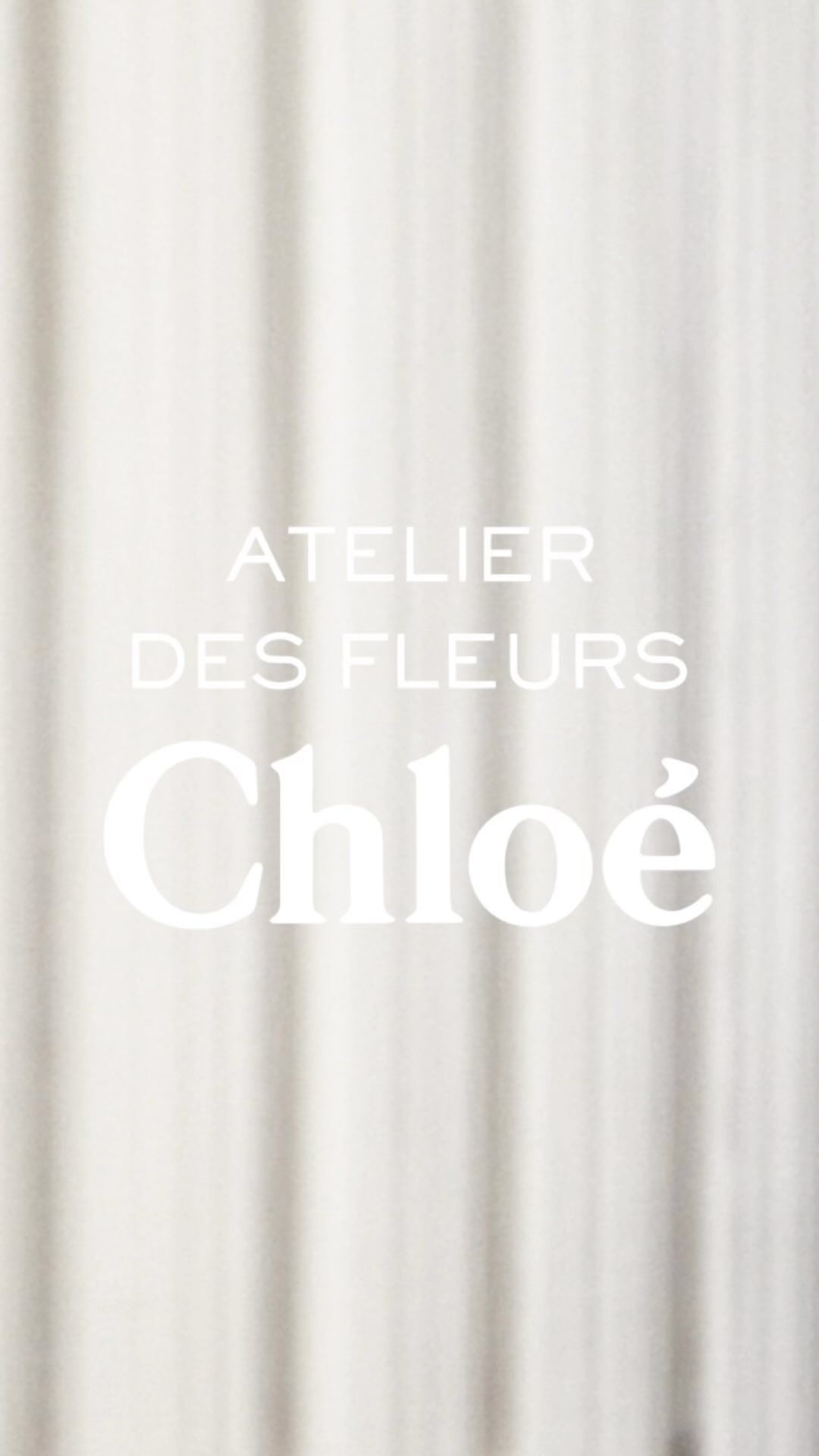 Chloe Atelier des Fleurs with soft focus on a textured white fabric background. Perfume and beauty ad with a minimalist aesthetic.