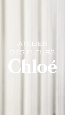Chloe Atelier des Fleurs with soft focus on a textured white fabric background. Perfume and beauty ad with a minimalist aesthetic.