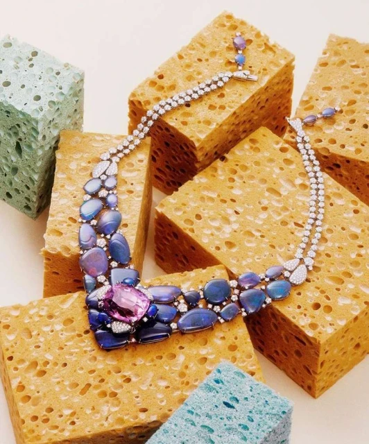 Elegant blue and white stone statement necklace on orange and blue porous blocks, creating a unique and high-fashion jewelry shot.